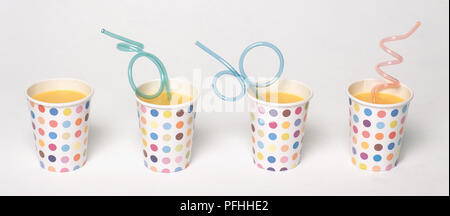 Vier mehrfarbige Pappbecher mit Orangensaft und twisted Strohhalme Stockfoto