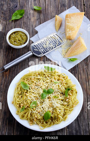 Italienische Pasta bucatini - Spaghetti mit Basilikum sauce Pesto, bestreut mit Pinienkernen und Parmesan auf weißem Schild auf Holzbretter, ingre Stockfoto