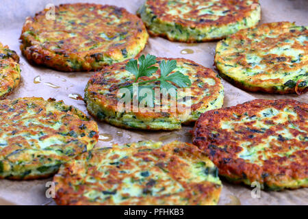 Lecker gebacken in Ofen köstliche geriebenen Zucchini, Petersilie und Schnittlauch Krapfen auf Backpapier, gesundes und einfaches Rezept, Ansicht von oben, close-up Stockfoto