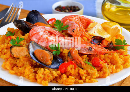 Teil der Gourmet Meeresfrüchte Valencia Paella mit Gambas, Muscheln auf herzhafte cremige Safran Reis mit Gewürzen und zitronekeile auf Platte, auf hölzernen Cu Stockfoto
