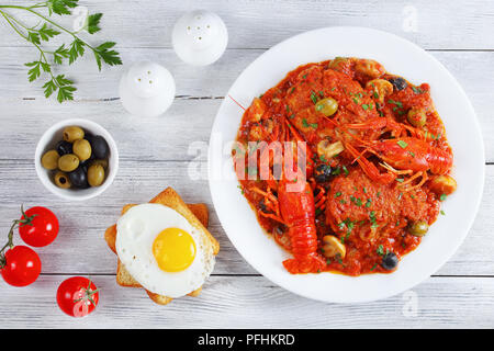 Huhn Marengo - Huhn Fleisch Eintopf mit crawfishies, gehackt Tomatensauce, Zwiebeln, Pilze, Oliven, auf die Platte an der Küche aus Holz Bretter mit Toast zu Stockfoto