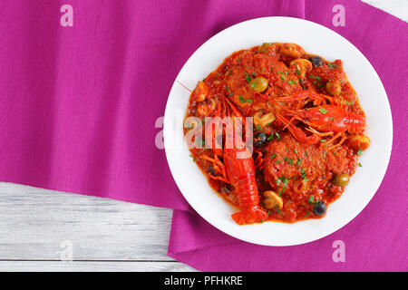 Huhn Marengo - Huhn Fleisch Eintopf mit crawfishies, gehackt Tomatensauce, Zwiebeln, Pilze, Oliven, auf die Platte an der Küche aus Holz Bretter mit Tisch mat Stockfoto