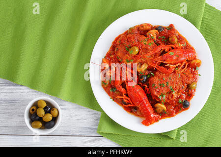 Huhn Marengo - Huhn Fleisch Eintopf mit crawfishies, gehackt Tomatensauce, Zwiebeln, Pilze, Oliven, auf die Platte an der Küche aus Holz Bretter mit grüne Lasche Stockfoto