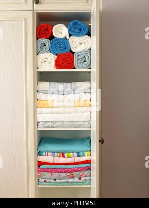 Beclothes und Handtücher ordentlich gestapelt und Bis im Schrank gerollt Stockfoto