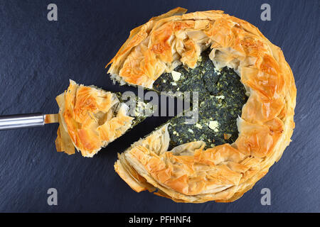 Köstliche goldene Kruste heißen griechischen Spinat Feta Käse Kuchen oder spanakopita in Scheiben geschnitten auf schwarzem Schiefer Fach, klassisches Rezept, Ansicht von oben Stockfoto