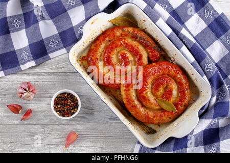 Lecker köstliche deutsche Bratwurst - runde gebratene Würstchen auf Holzspieße in braten Teller auf alten rustikalen Holztisch mit Küchentuch, vie Stockfoto