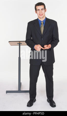 Mann in dunklem Anzug stehen und stehen und Lächeln, Vorderansicht. Stockfoto