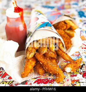 Frittierte Stücke von Fisch und Chips in Papiermembran, neben Flasche Tomatenketchup Stockfoto