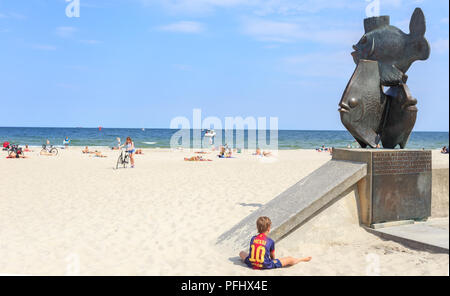 Gdynskie Rybki - eine Besetzung von Metall durch Adam Smolana, zeigt drei Fische, am Eingang der Zentrale Strand entfernt. Ein kleiner Junge spielt in Shirt von Messi Stockfoto