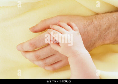 Baby's Hand oben auf die Hand eines Mannes, oben betrachten. Stockfoto