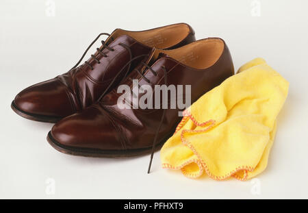 Gelbes Tuch durch ein Paar von braunen Leder Herrenschuhe, Seitenansicht. Stockfoto