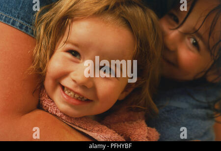 Zwei lächelnde junge Mädchen eingewickelt in Tücher umarmte die Frau, schließen. Stockfoto