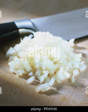 Fein gehackte Zwiebel und ein Messer auf einem Holzbrett, Seitenansicht. Stockfoto