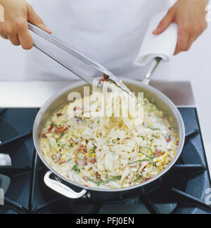 Fettuccine Pasta mit Käse und Gemüse Sauce aus Pfanne mit Metall Zange, hohe Betrachtungswinkel anheben Stockfoto