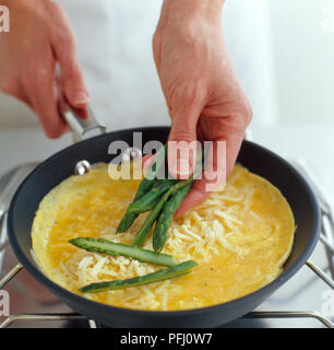 Spargelspitzen über Omelette kochen in der Pfanne, hohe Betrachtungswinkel gelegt werden Stockfoto