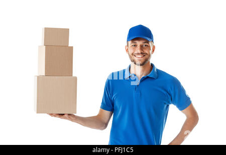 Lächelnd Delivery Man holding Stapel von Kartons auf weißem Hintergrund Stockfoto