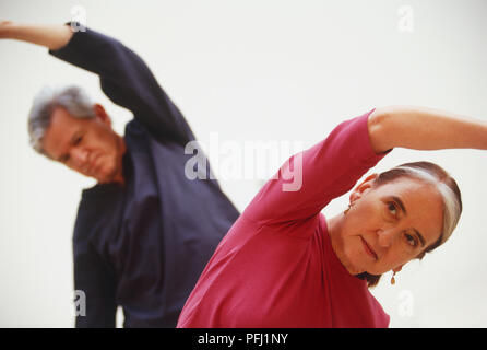Reifer Mann und Frau eine seitliche Streckung mit den Armen über dem Kopf Stockfoto