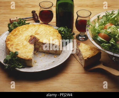Schinken und Ei Torte, eine Scheibe entfernt, eine Platte mit gemischtem Salat, und zwei Gläser und eine Flasche Rotwein Stockfoto