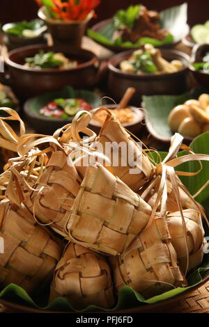Ketupat Lebaran, die traditionelle feierliche Reisgericht mit Kuchen mit mehreren Beilagen; beliebt während Eid feiern. Stockfoto