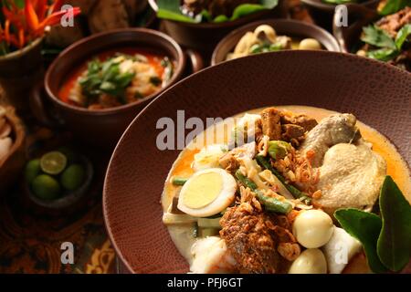 Ketupat Lebaran, die traditionelle feierliche Reisgericht mit Kuchen mit mehreren Beilagen; beliebt während Eid feiern. Stockfoto