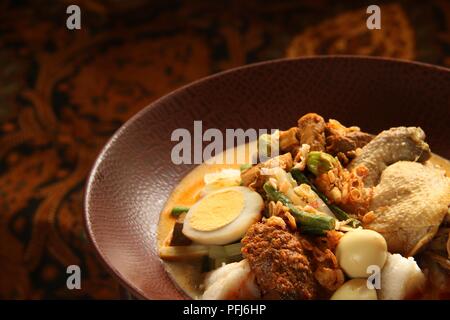 Ketupat Lebaran, die traditionelle feierliche Reisgericht mit Kuchen mit mehreren Beilagen; beliebt während Eid feiern. Stockfoto