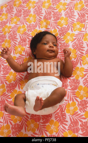 Neugeborenes Baby Boy tragen Windel liegen auf bunt gemusterten Tuch mit Armen und Beinen in der Luft, Blick von oben. Stockfoto