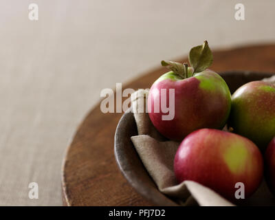 Äpfel ruht auf Tuch in eine hölzerne Schüssel auf einem Holzbrett Stockfoto