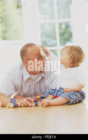 Mann mit Zeigefinger ruht auf Spielzeug, mit Kind, bis erreicht und seinen Kopf berühren Stockfoto