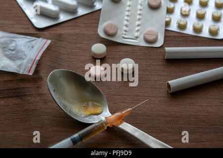 Droge Spritze und gekocht Heroin auf Löffel mit Pillen der Ekstase und Tabak Stockfoto
