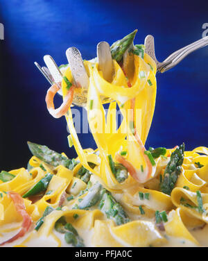 Pasta Schaufel aufnehmen Portion Tagliatelle, Spargel und Schinken in Rahmsauce Stockfoto
