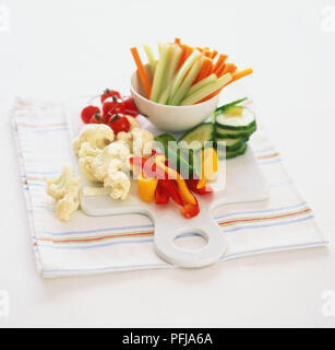 Schüssel mit Gurken Sticks und Karotten Sticks, neben Röschen Blumenkohl, Streifen von Pfeffer, Gurkenscheiben und Cherry Tomaten, auf einem Schneidebrett Stockfoto