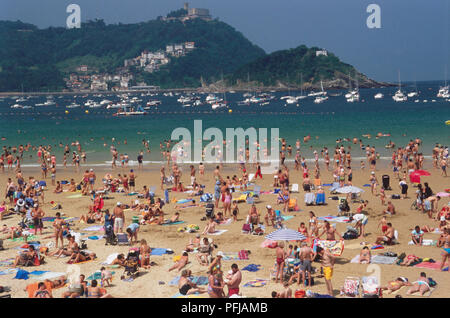 Europa, Spanien, Nordspanien, San Sebastian, La Concha, sandigen Bucht voller Sonnenanbeter, Schwimmer und Boote in See Stockfoto