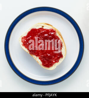 Scheibe Brot mit Butter und Marmelade auf einem Teller, Ansicht von oben Stockfoto