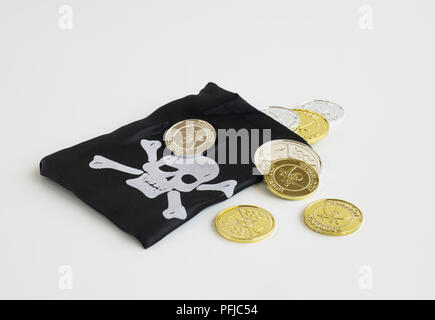 Pirate's Geldbeutel mit totenkopf und gekreuzten knochen auf und gefälschte Gold und Silber Münzen Stockfoto