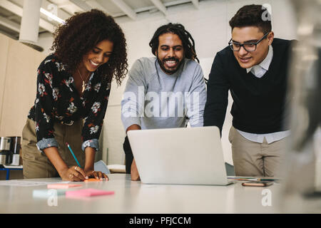 Unternehmer und die Frau, die an einem Notebook arbeitet als Team zusammen. Unternehmerin Notizen während einer Diskussion mit den Kollegen im Büro. Stockfoto