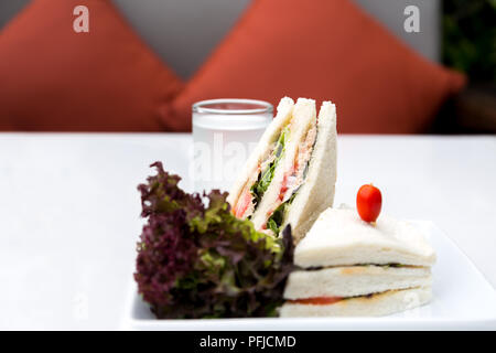 Thunfisch Sandwiches und Glas Wasser mit roten Kissen im Hintergrund Stockfoto