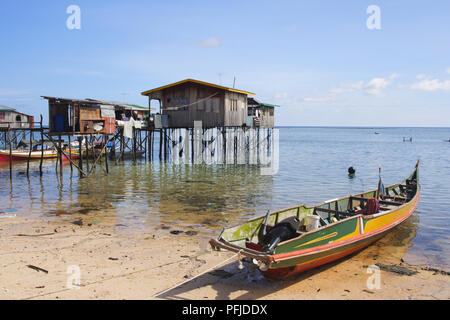 Malaysia, Sabah, Mabul Island, Pfahlbauten im Meer, und ein Boot am Strand günstig in der Nähe, close-up Stockfoto