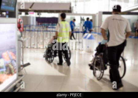 Verschwommenes Konzept Hausmeister drücken ältere Menschen im Rollstuhl am Flughafen Stockfoto