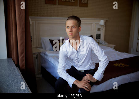 Eine junge stilvolle und Geschäftsmann zu einem Geschäftstermin in einem Hotel Zimmer geht. Er setzte auf ein weißes Hemd und Hose. Stockfoto