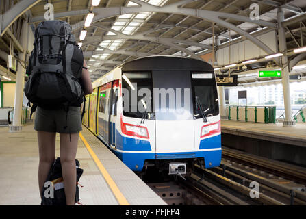 Konzeptionelle Frau Reisenden mit Rucksack warten auf Sky Train Stockfoto