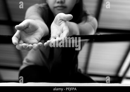 Junge Frau Opfer Hand erreichen, um Hilfe von einem Metal bars in Schwarz und Weiß Stockfoto