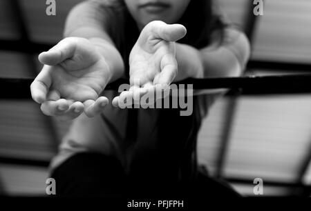 Junge Frau Opfer Hand erreichen, um Hilfe von einem Metal bars in Schwarz und Weiß Stockfoto