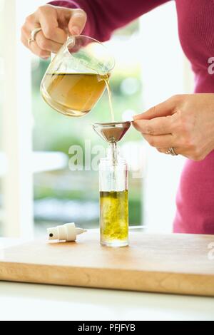 Woman's Hand gießen Kamille Tee, Honig und Hanf Öl Mischung aus Kanne in Flasche mit Pumpspray oben (die natürliche baby Cleansing Lotion) Stockfoto