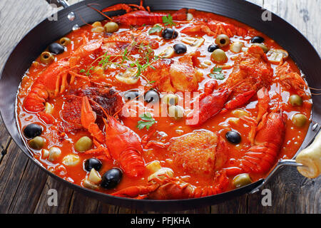 In der Nähe von Huhn Marengo - Huhn Fleisch Eintopf mit crawfishies, gehackt Tomatensauce, Zwiebeln, Pilze, Oliven, Thymian in Skillet auf Holz Küche b Stockfoto