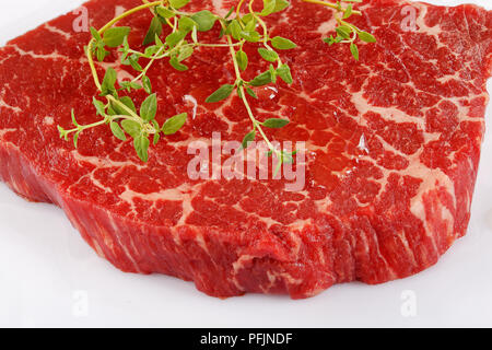 Nahaufnahme der Marmorierte Rindfleisch Roastbeef Steak mit Thymian auf weißem Hintergrund, Ansicht von oben Stockfoto