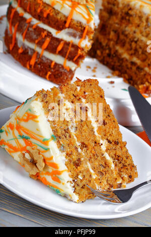 Stück klassische Karottenkuchen mit Cream Cheese frosting mit Walnüssen dekoriert und mit bunten Ganache mit ganzen Kuchen auf Hintergrund beträufelt, Verti Stockfoto