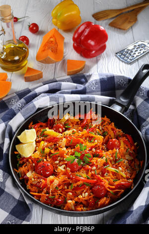 Ein Topf, Teller - Hot pumpkin Salat mit Tomaten, Paprika, Zwiebel, bestreut mit Sesam und die Pinienkerne in einer Pfanne mit Zutaten auf Backgr Stockfoto