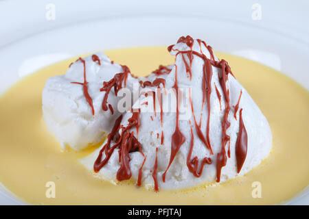 Eine schwimmende Insel oder Bird's Milch ist ein Dessert französischer Herkunft, bestehend aus Baiser schwimmend auf Creme Anglaise in Weiß breite Felge Teller serviert, aut Stockfoto