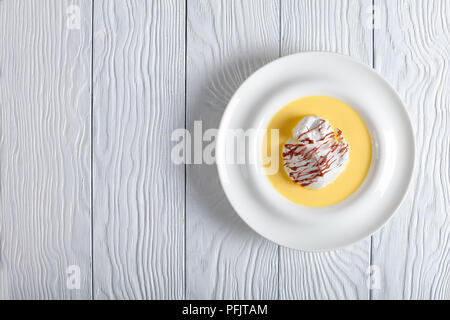 Eine schwimmende Insel oder Bird's Milch - ein französischer Nachtisch, bestehend aus Baiser schwimmend auf Creme Anglaise und beträufelt mit Ganache, verbindlich Stockfoto