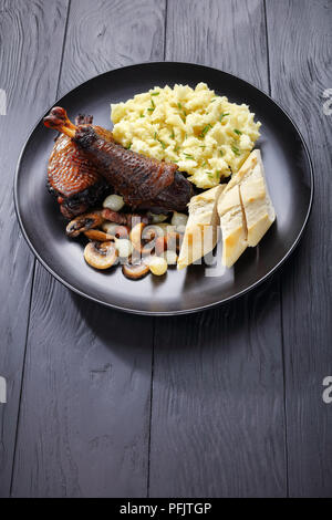 Ein Teil von Coq au Vin - klassische französische Hühnereintopf auf schwarze Platte mit Kartoffelpüree und französischem Brot serviert, vertikale Ansicht von oben Stockfoto